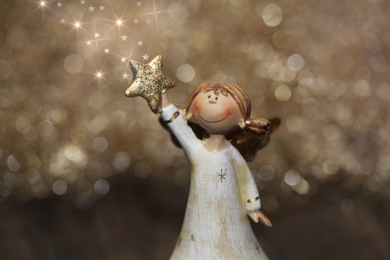 Smiling Christmas angel figurine holding a gold star in front of a gold sparkly background.